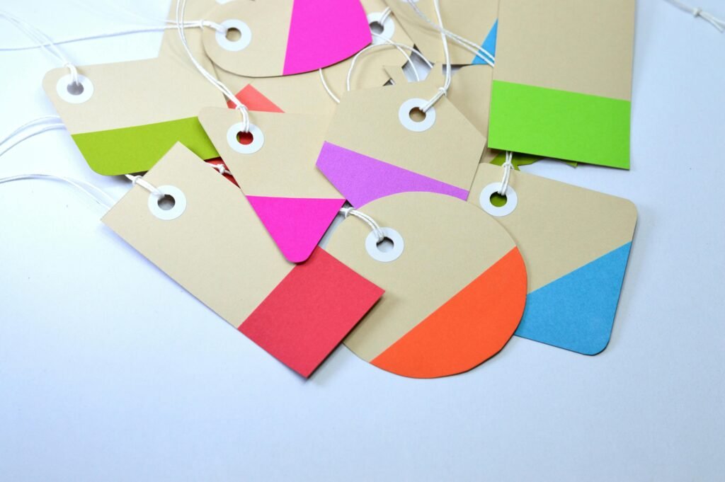 Bright and colorful paper card tags arranged on a white surface, showcasing vibrant design and shapes.